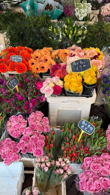 A vibrant display of fresh flower bouquets at a florist shop, showcasing an assortment of colourful blooms including pink roses, red tulips, yellow roses, and bright orange gerbera daisies arranged in