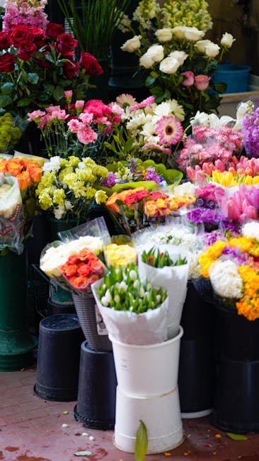 A vibrant display of freshly arranged flower bouquets at a florist shop, featuring a variety of colorful blooms including pink carnations, white roses, yellow and purple chrysanthemums, and tulips wra